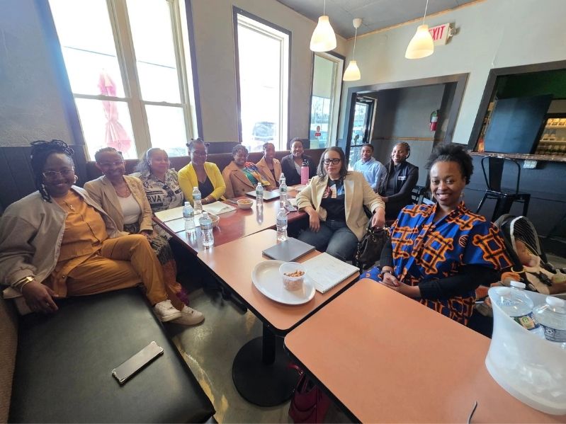 CADI team members and partners gathered around tables at a community meeting